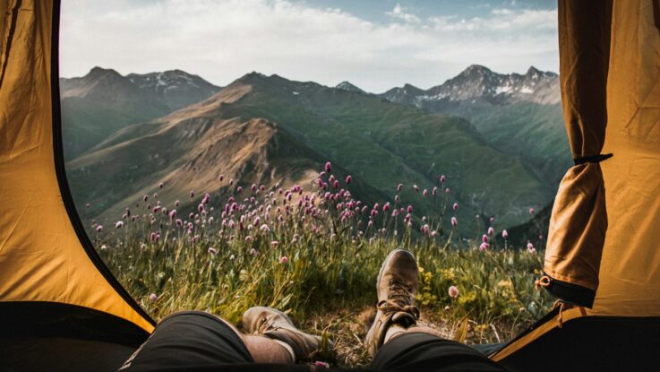 person lying inside tent and overlooking mountain